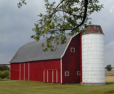dark red barn with bright white silo...