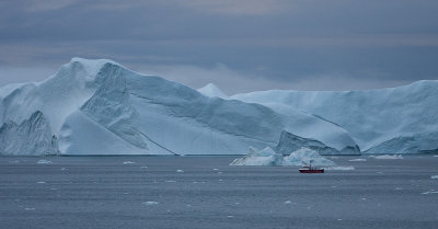 Iceberg Towers over a Fishing Boat