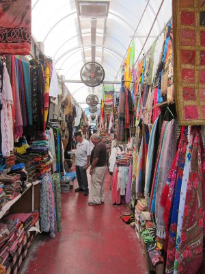 Jaffa flea market-covered alleyway dominated by clothes and fabric