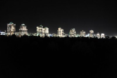 Marble-clad apartment blocks lit up at night behind the dark central portion of Independence Park