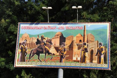 Billboard with the statues from the Airport Roundabout in front of the historic sites of Turkmenistan