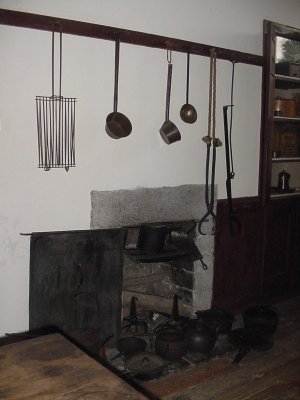 Kitchen utensils hanging above the open hearth used for cooking.