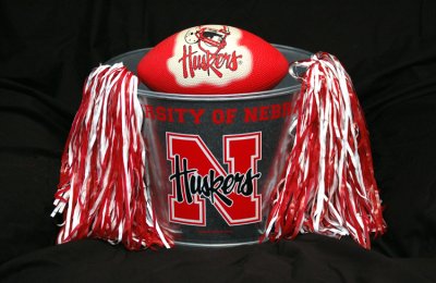 My mother inlaw sent these Crimson Pom Pons for my daughter, to try and encourage her to root just a little for Bama. She was also kind enough to pick up these Husker buckets (There's a smaller one inside the larger one shown) and send them as well. I borrowed my daughter's Pom Pons and put them in my new bucket, along with an old rubber Husker Ball I already owned. Then I went about the business of setting this shot up. Thanks Oma Bev. These are very cool!