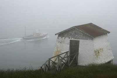 A lobster boat passes one of the buildings at Burnt Coat.