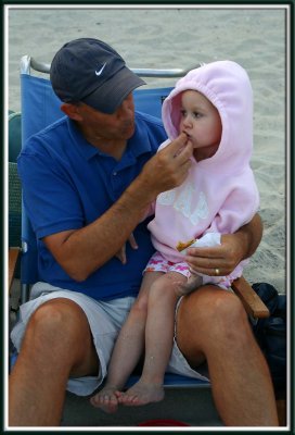 Grampy feeds Kylie her cookie (because her hands are sandy)