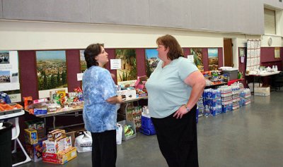 6-26: Volunteers Donna (r) and Heather chat in front of donations while planning next day's breakfast for visiting firefighters