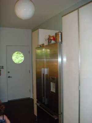 ikea cabinets to each side of fridge. round light fixture & window in door