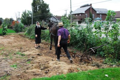 Young Amish couple tilling garden in Intercourse, PA