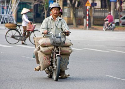 Motorscooters often transport  cargo as well as people. This tiny scooter is carrying two people as well as 200 kg in the bags.