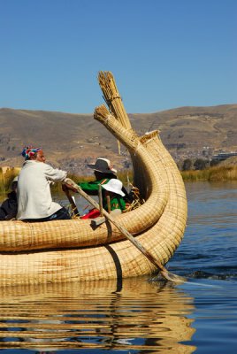 Uros man paddling a reed boat