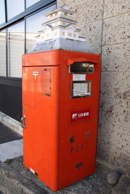 Postbox outside Shiroishi Station with castle replica