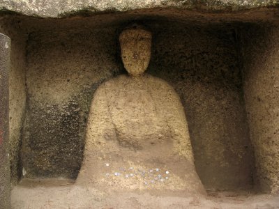 Weathered Buddhist image with coin offerings