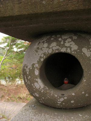 Tiny daruma doll inside a stone lantern