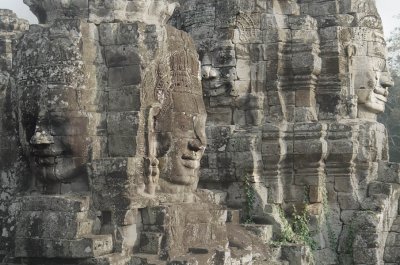 In Cambodia, Avalokitesvara or Lokesvara is the spiritual son of the transcending Dhyani-Buddha Amitabha - the image of whom he carries on his chignon. He personifies, as Paul Mus has explained the notion of providence, unknown to primitive Buddhism. He is the Lord of the World from whom all gods emanate, himself the god of morality and graciousness - a masculine replica of Kouan-Yin, the other dominant figure in far eastern Buddhism. The face often has a third eye on the forehead and the heads can be multiple and in tiers. In the living architecture of the towers of the Bayon, by the turning of his four faces to the four cardinal points, he is omnipresent.