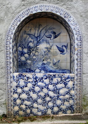 A beautiful fountain with tiles of  birds and hydrangea