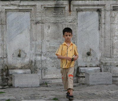 Boy against a backdrop of washing stalls at a Mosque