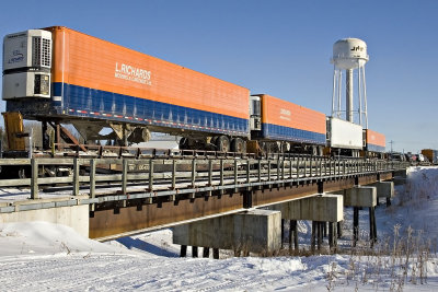 Trailers on flatcars crossing Store Creek in Moosonee