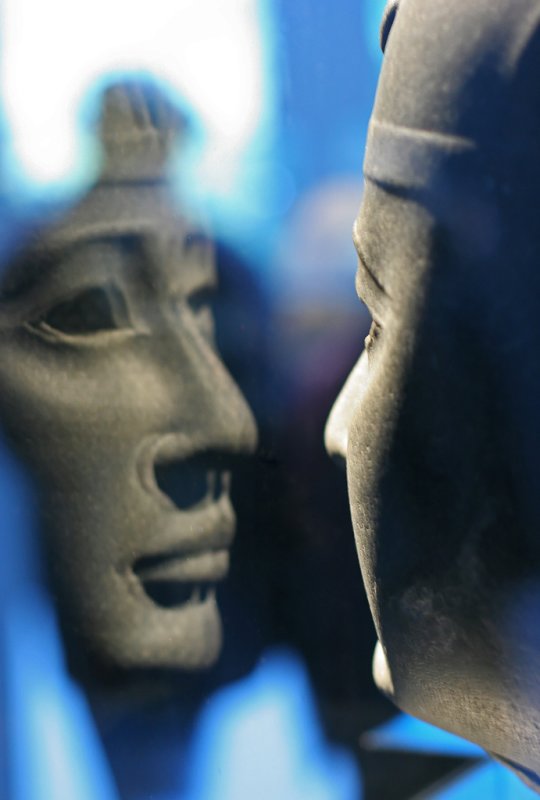 Reflet d'une tête scuptée dans sa vitrine