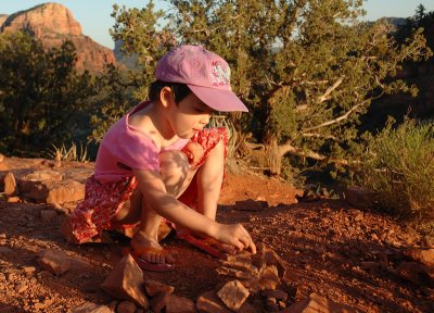 She is building blocks with little red rocks.