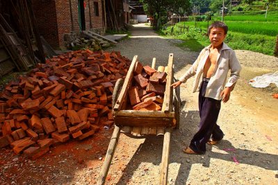 0271 Young boy loading bricks that he will haul to a construction site.