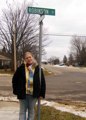 Salena Marie Robinson standing under the street sign for Robinson Street, Newberry Michigan. The street was named fro her great paternal grandfather, Everett Daniel Robinson. Her grandfather, Harold Everette Robinson laid most of the sidewalks in Newberry. Salena Marie Robinson is in posession of an original copy of this photograph