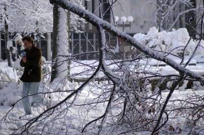 A student protects his papers from blowing snow with a branch down nearby