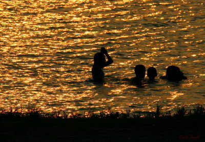 CHILDREN PLAYING IN THE WATER AT SUNSET