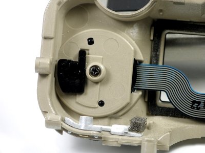 Note that the Mode Dial assembly is put on to the 
cover from the top side, with the ribbon cable thru 
the slot in the cover. There are two small protrusions
and a rectangular block cast on the black plastic 
bottom of the Mode Dial assembly for orientation. 
Then put a screw in the center and tighten.Then the plastic keeper
