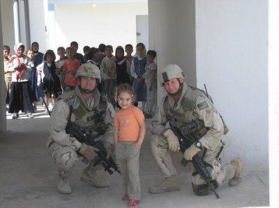 Capt Borders and SrA Goliglowski (506th / 822nd SFS  Kirkuk Air Base) with a young Iraqi child displaying her new shoes.