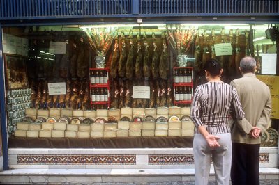 A Sevilla couple contemplates a display of hams, cheeses and wines