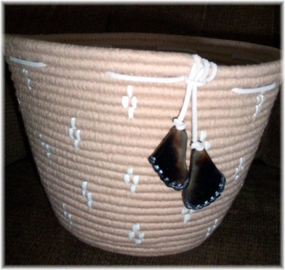 Basket is 8 inches high and is trimmed with white leather strings and carved deer toe clackers.