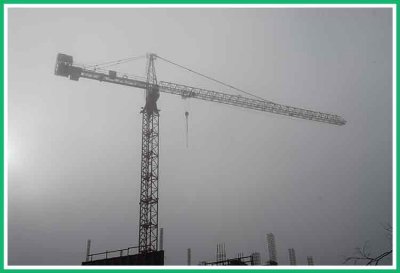 Construction crane reaches into the early morning fog.