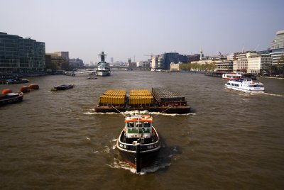 Boat towing cargo under Tower Bridge