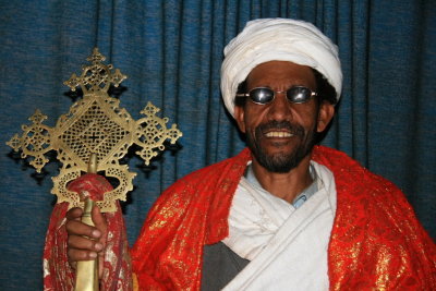 A priest shows off a traditional cross.  The sunglasses, we later learned, are worn because of camera flashes.