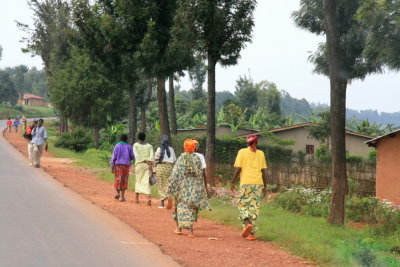 Women dressed in colorful outfits walk by the well-maintained paved road from Kigali to Ruhengeri