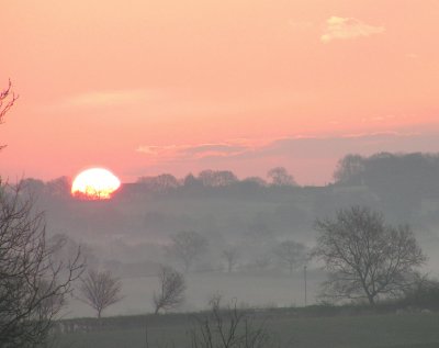 Sun rising over misty valley