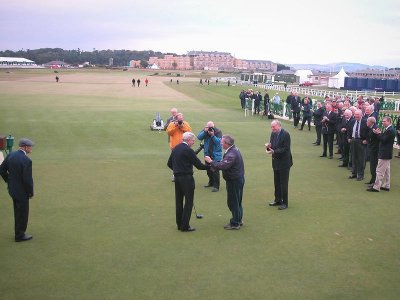 The new Captain presents the gold sovereign to the caddy who retrieved the ball
