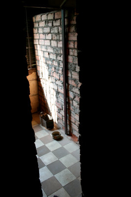 A Tuol Sleng Prison cell with an excrement pot and a bowl on the floor.