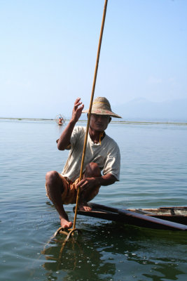 The fishermen use a long pole to poke around inside baskets to frighten any fish caught inside.