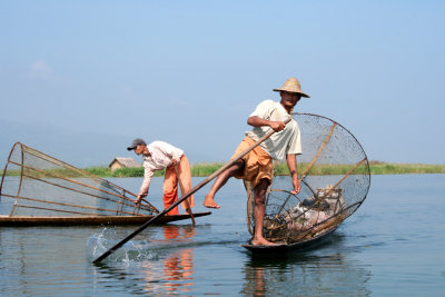The fisherman is reaching for the oar with his leg.