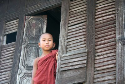 A young monk peering outside the window of the monastery.