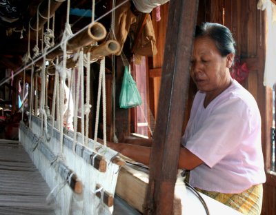 Another woman intently at work on the weaving machine.