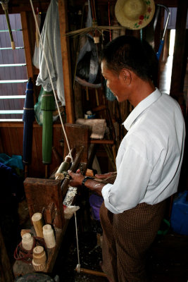 A side view of the man using the lathe on the bamboo.