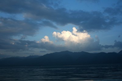 More dark and light clouds with mountains in the horizon.