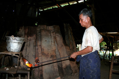 Another man with hot molten glass in the shape of a container.