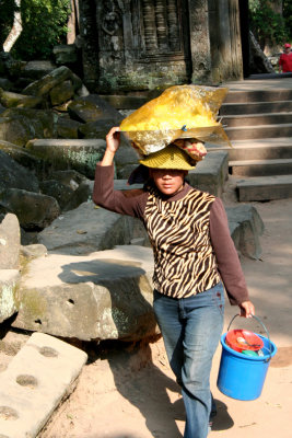 A woman walking through the temple carrying a load on her head.