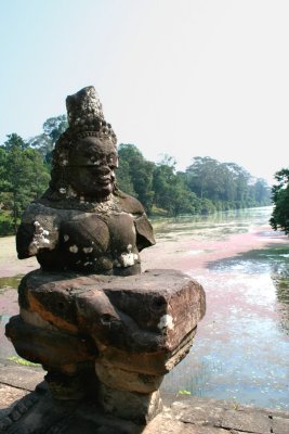 A demon statue with the moat in the background.