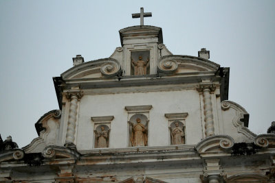 The top of the church adorned with statues of saints and a cross.
