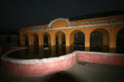 The front of the pool and arches at night.