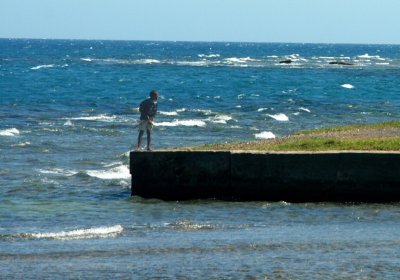 A little boy was standing at the water's edge with the waves crashing around him.